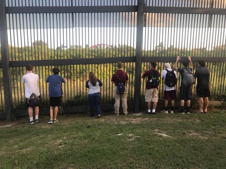 Students pose at the
border wall separating Brownsville from Matamoros, Mexico.