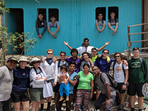 Students pose in front of one of the houses they painted in Lima, Peru.